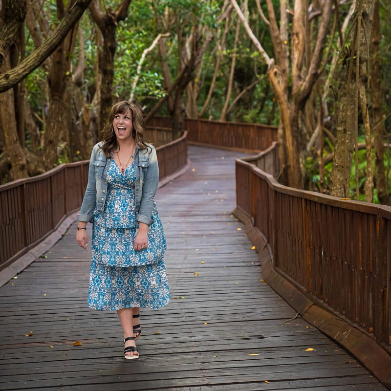 Christine walking down wooden jungle path in Mexico with a big smile.