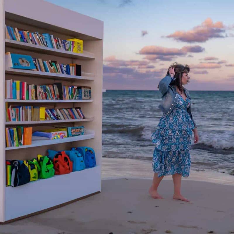 Chrissy walking from her classroom library onto the beach